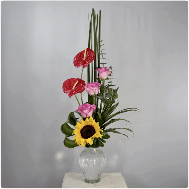 Arreglo floral de rosasanturio girasol follaje con base de cristal